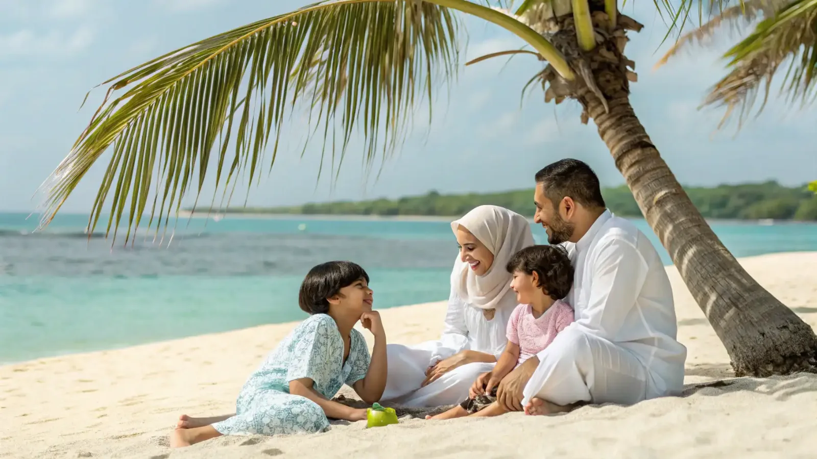 Family relaxing under a palm tree on a beach in Bali